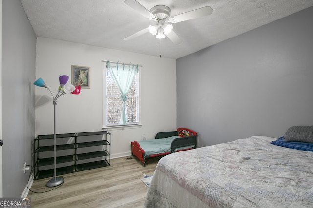 bedroom with ceiling fan, light hardwood / wood-style floors, and a textured ceiling