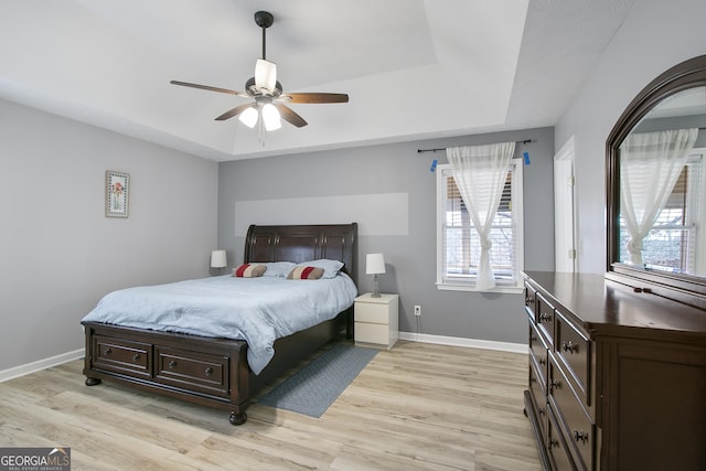 bedroom featuring a tray ceiling, light hardwood / wood-style floors, and ceiling fan