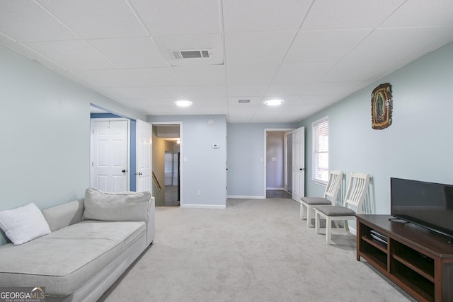 living room with a paneled ceiling and light colored carpet