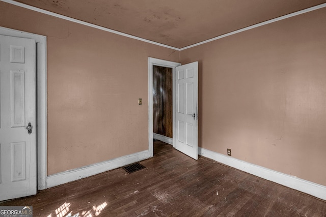 spare room featuring dark wood-type flooring and ornamental molding