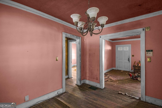 unfurnished dining area with crown molding, dark wood-type flooring, and a notable chandelier