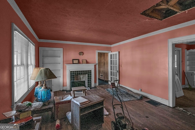 living room with a tile fireplace, hardwood / wood-style floors, ornamental molding, a textured ceiling, and built in shelves