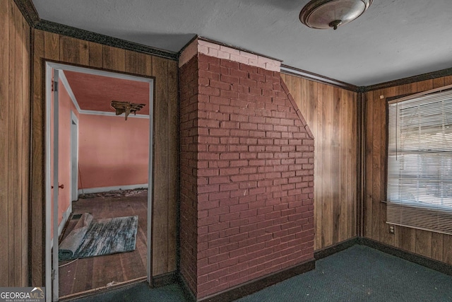 interior space with ornamental molding, brick wall, a textured ceiling, and wooden walls