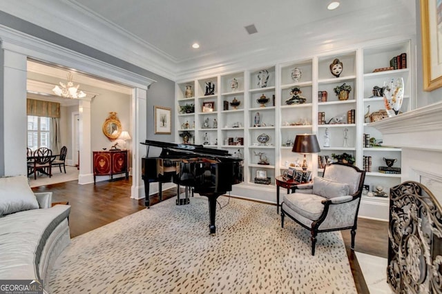 living area featuring crown molding, a chandelier, hardwood / wood-style floors, and built in features