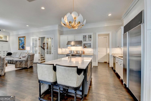 kitchen featuring pendant lighting, white cabinetry, built in refrigerator, and stove