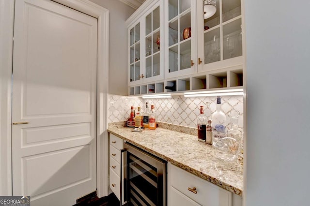 bar featuring wine cooler, light stone countertops, decorative backsplash, and white cabinets