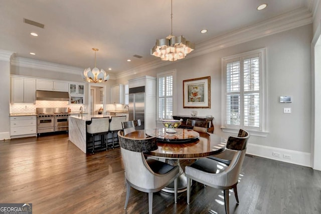 dining space with crown molding, a notable chandelier, sink, and dark hardwood / wood-style floors