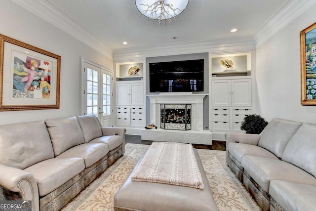 living room featuring hardwood / wood-style flooring, built in features, a fireplace, ornamental molding, and french doors