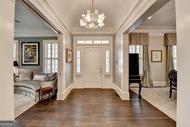 entrance foyer with dark wood-type flooring, ornamental molding, and a chandelier