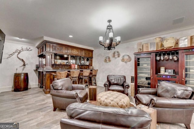 living room with an inviting chandelier, crown molding, light hardwood / wood-style flooring, and bar area