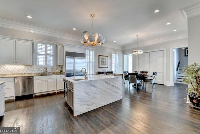 kitchen featuring sink, white cabinetry, decorative light fixtures, a center island with sink, and appliances with stainless steel finishes