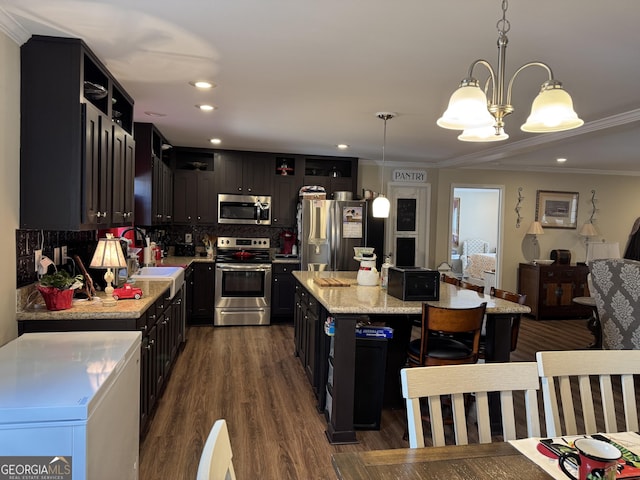 kitchen featuring pendant lighting, appliances with stainless steel finishes, a center island, and sink