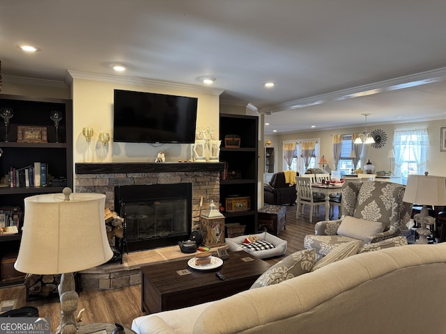 living room with hardwood / wood-style flooring, crown molding, a stone fireplace, and an inviting chandelier