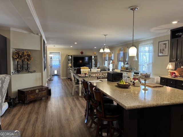 kitchen featuring a large island, hanging light fixtures, a kitchen breakfast bar, dark hardwood / wood-style floors, and ornamental molding