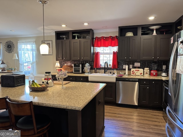 kitchen featuring pendant lighting, tasteful backsplash, sink, ornamental molding, and stainless steel appliances