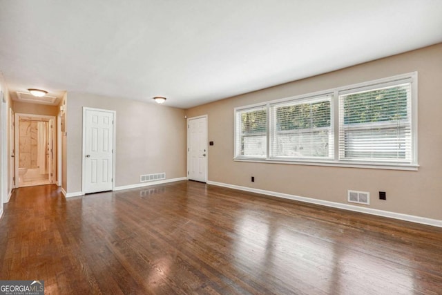 empty room with plenty of natural light and dark hardwood / wood-style floors