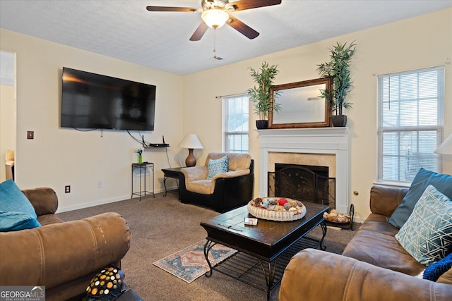 carpeted living room with a tiled fireplace, ceiling fan, and a textured ceiling