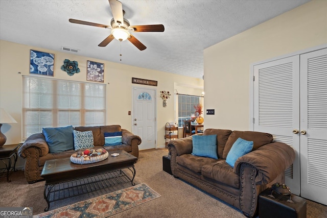 carpeted living room featuring ceiling fan and a textured ceiling