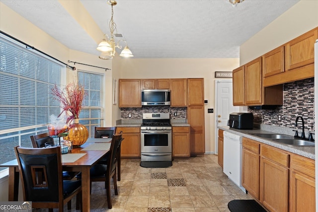 kitchen with sink, an inviting chandelier, hanging light fixtures, stainless steel appliances, and backsplash