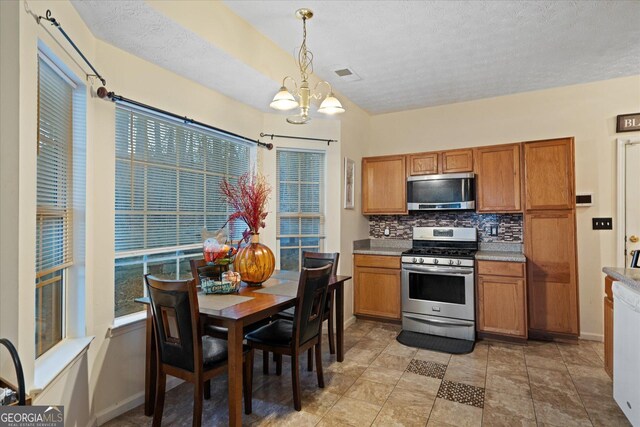 kitchen featuring tasteful backsplash, an inviting chandelier, hanging light fixtures, a textured ceiling, and stainless steel appliances