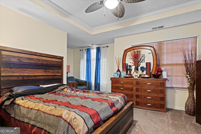 bedroom with ornamental molding, light colored carpet, ceiling fan, and a tray ceiling