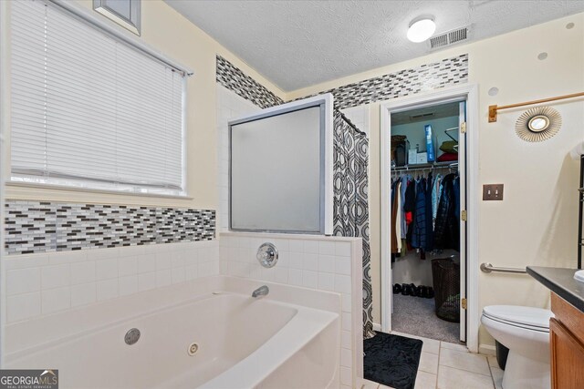 full bathroom featuring independent shower and bath, tile patterned flooring, vanity, toilet, and a textured ceiling