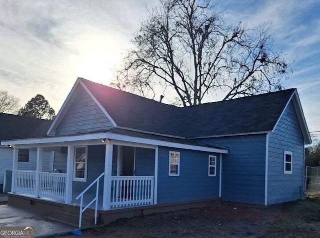 back house at dusk featuring a porch