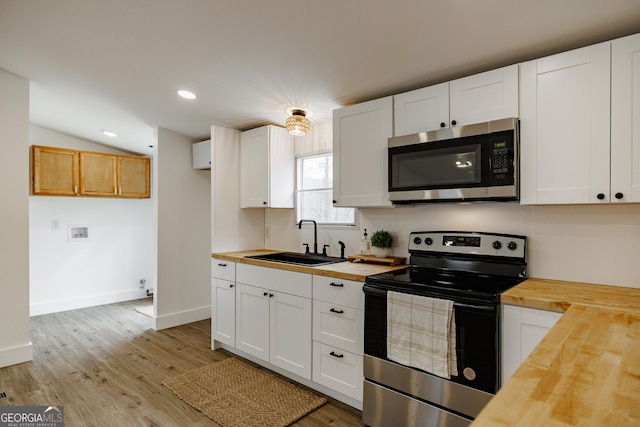 kitchen with white cabinetry, appliances with stainless steel finishes, butcher block counters, and sink