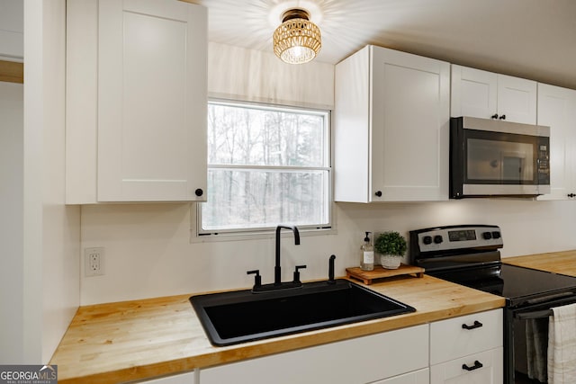 kitchen featuring butcher block counters, sink, range with electric cooktop, and white cabinets