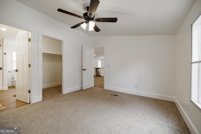 unfurnished bedroom featuring a walk in closet, carpet floors, ceiling fan, and vaulted ceiling