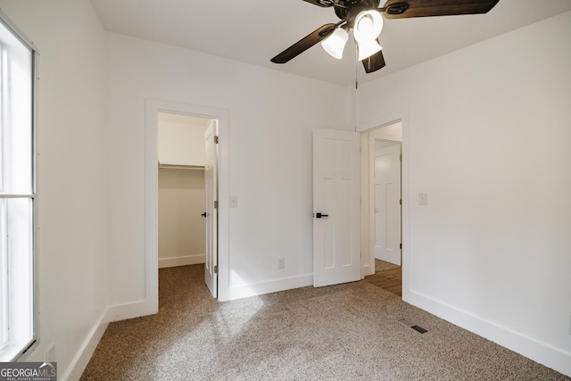 unfurnished bedroom featuring ceiling fan, carpet flooring, a closet, and a spacious closet