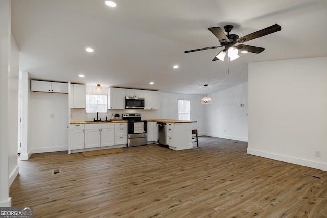 kitchen featuring sink, light wood-type flooring, appliances with stainless steel finishes, pendant lighting, and white cabinets