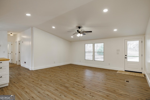 unfurnished living room featuring vaulted ceiling, ceiling fan, and light hardwood / wood-style flooring