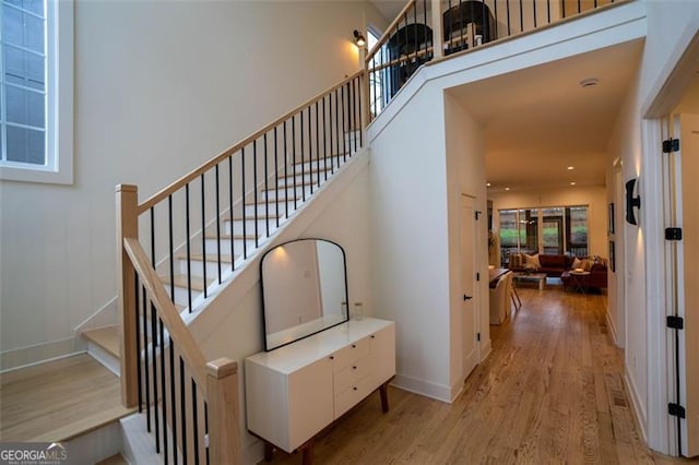 stairs with wood-type flooring and a towering ceiling