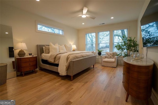 bedroom featuring multiple windows, light hardwood / wood-style floors, and ceiling fan