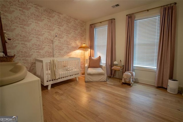 bedroom with hardwood / wood-style flooring, sink, and a crib