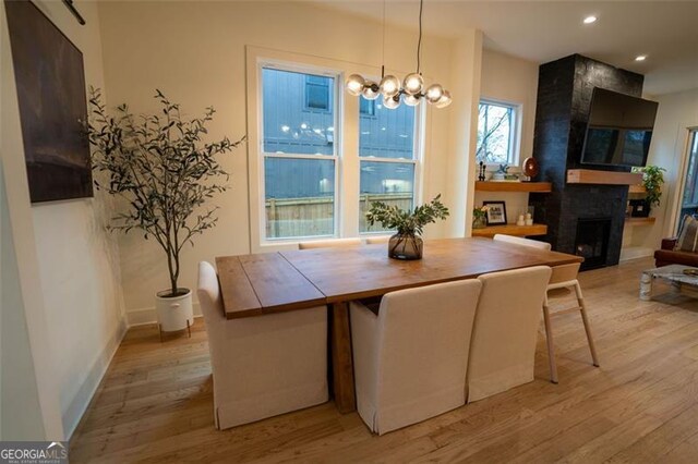 dining room featuring a notable chandelier, a large fireplace, and light wood-type flooring