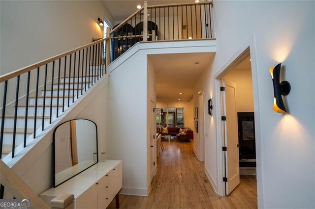 hallway with a towering ceiling and light hardwood / wood-style flooring