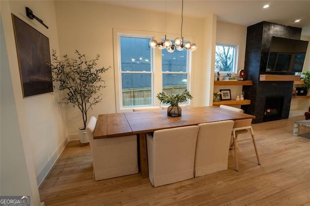 dining room featuring a notable chandelier, light hardwood / wood-style flooring, and a large fireplace