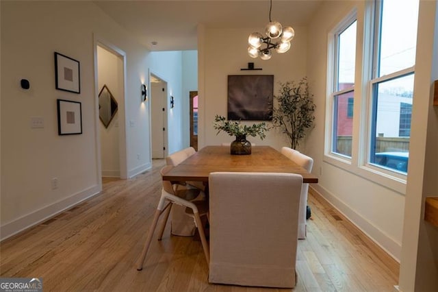 dining space with light hardwood / wood-style flooring and a notable chandelier