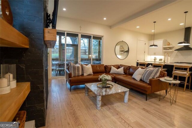 living room featuring beamed ceiling, sink, and light wood-type flooring