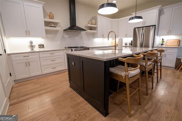 kitchen featuring wall chimney range hood, stainless steel appliances, sink, and white cabinets