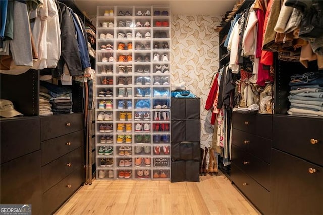 walk in closet with light hardwood / wood-style floors