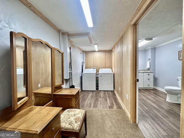 clothes washing area featuring crown molding, light hardwood / wood-style flooring, washer and dryer, and a textured ceiling