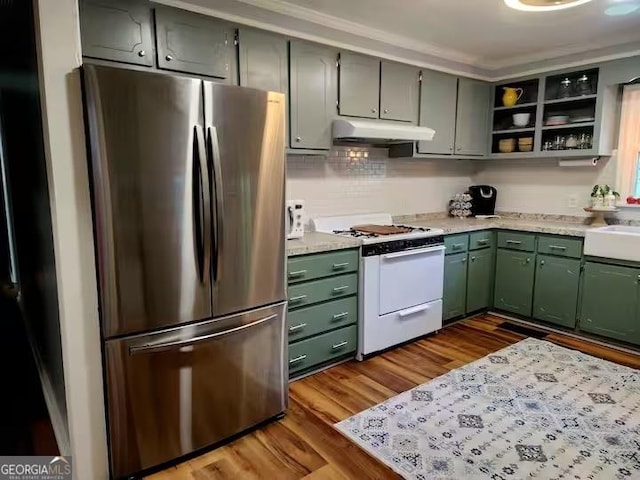 kitchen with hardwood / wood-style floors, sink, stainless steel fridge, green cabinets, and white gas stove