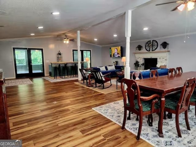 dining space with lofted ceiling, hardwood / wood-style floors, crown molding, and a fireplace