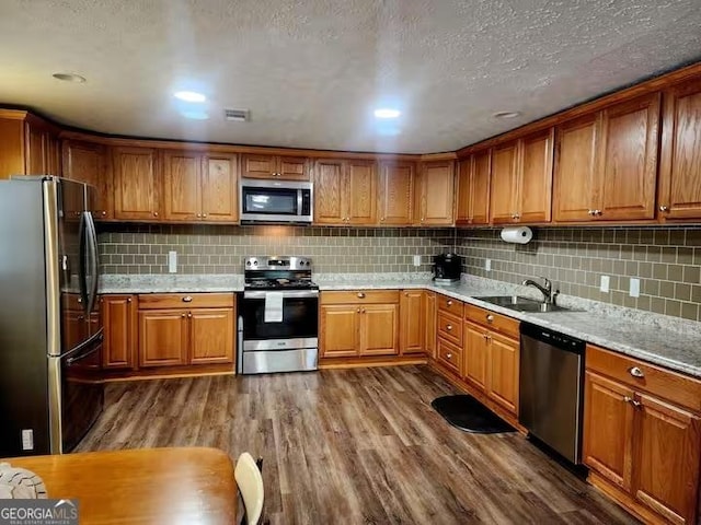 kitchen featuring appliances with stainless steel finishes, sink, backsplash, and dark hardwood / wood-style floors