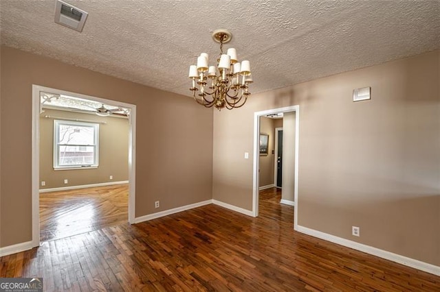 empty room with an inviting chandelier, a textured ceiling, and dark hardwood / wood-style flooring