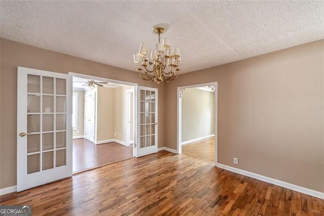 unfurnished room featuring an inviting chandelier, dark wood-type flooring, french doors, and a textured ceiling