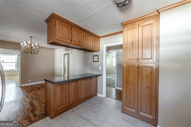 kitchen featuring an inviting chandelier, kitchen peninsula, a textured ceiling, and light hardwood / wood-style flooring